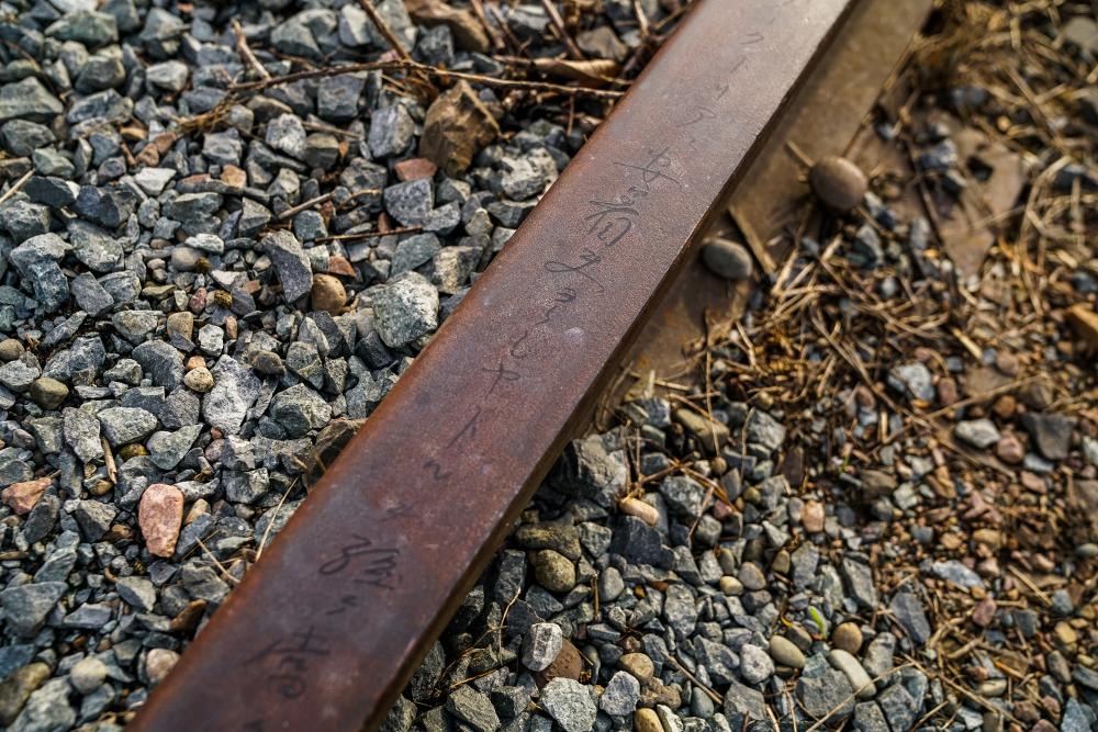 A detail of handwritten text from a letter written by Captain Matsuzo Sakamoto etched on the Prairie Line Trail train tracks by the artist. Courtesy of City of Tacoma.